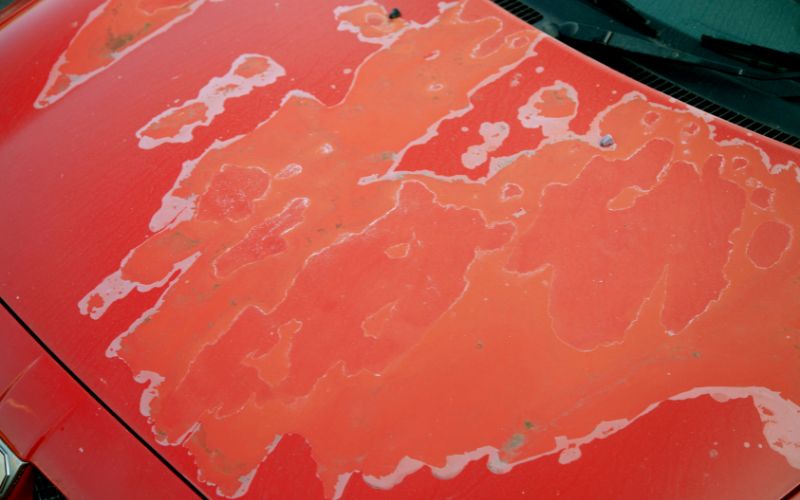 peeling paint on the hood of a red car
