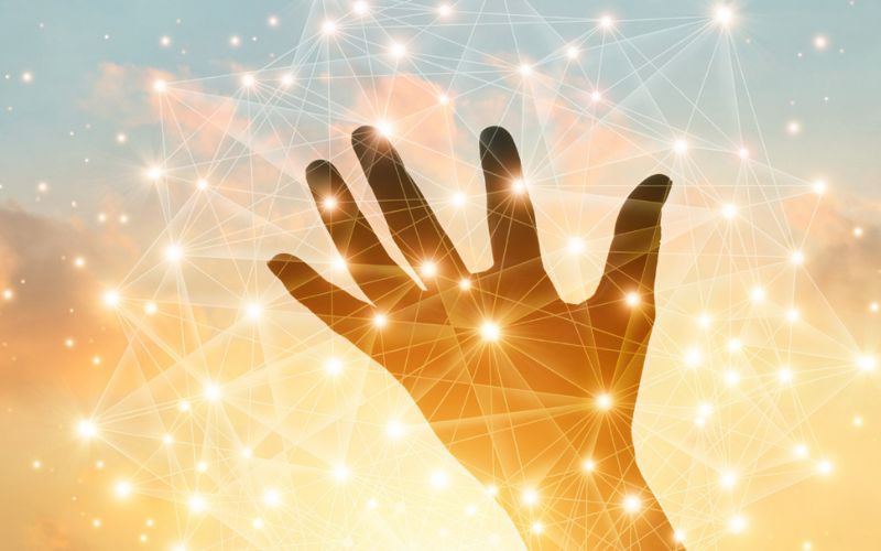 silhouette of a hand palm up backdropped by a cloud-filled, sunset sky overlayed by data points