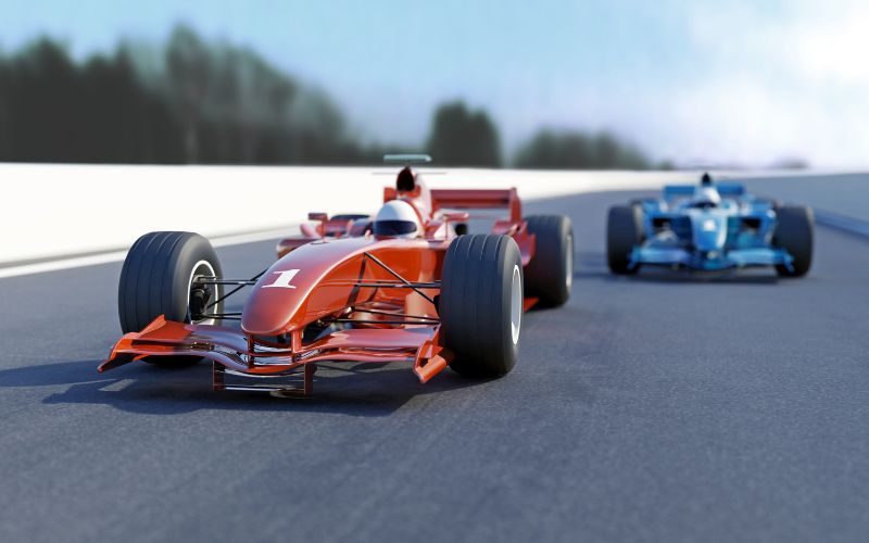 red race car followed by an out of focus blue car on a race track