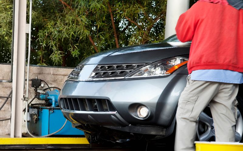 silver SUV emerging from car wash tunnel with an employee standing by