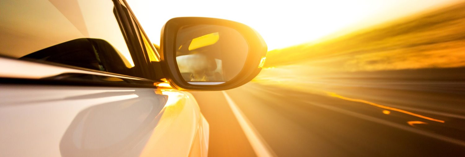 vehicle driving down road bathed in golden sunlight