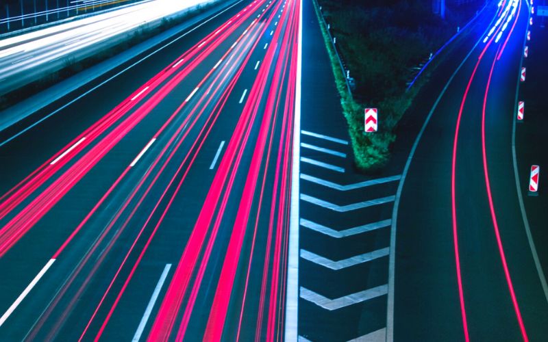 highway at night with an off ramp with lines that appear to be blurred speeding cars