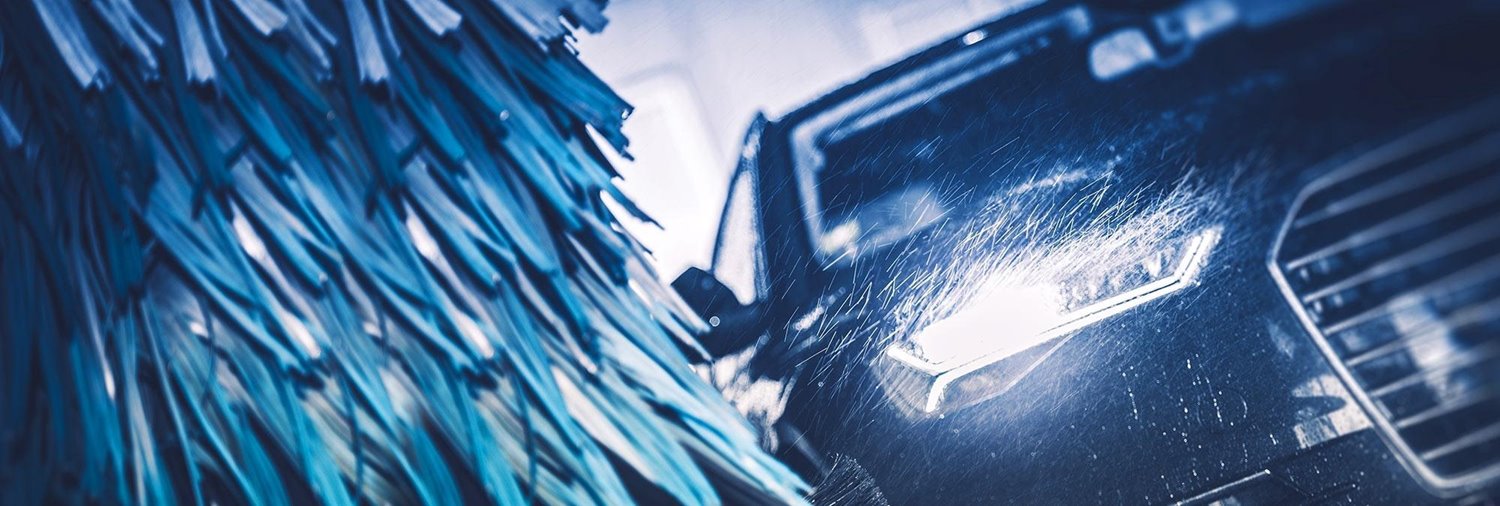 dark colored vehicle shown at an angle going past a blue wrap in a car wash