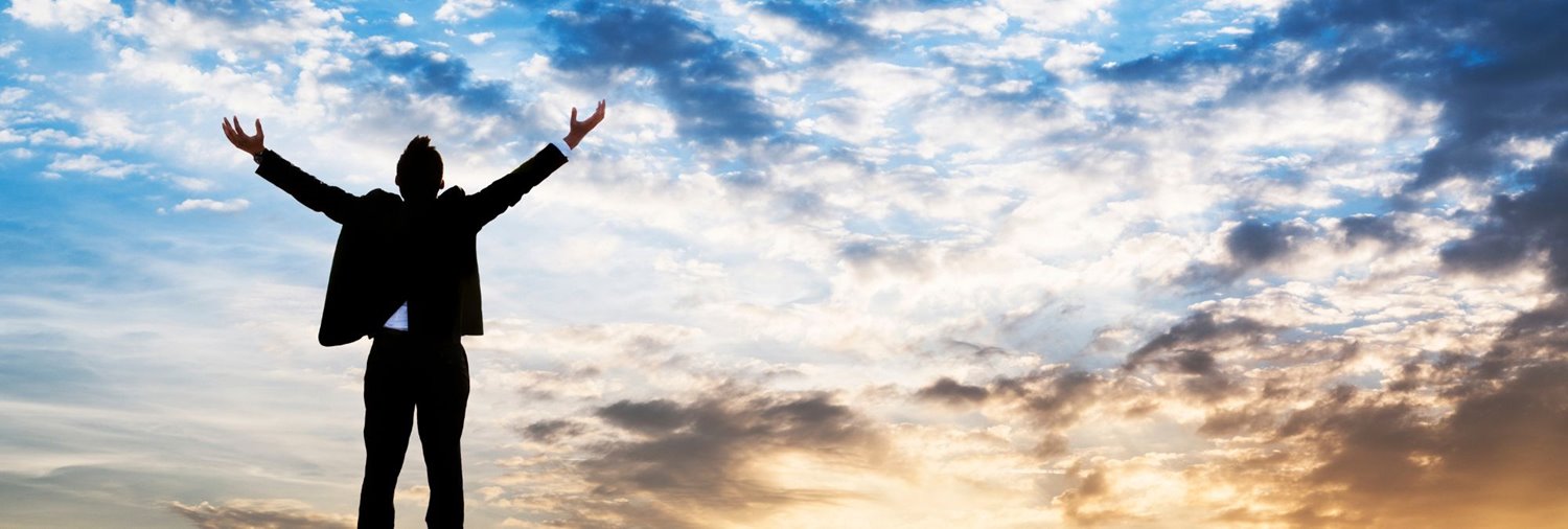 Man with arms in air on top of a mountain