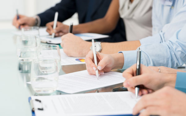 row of people at a table writing