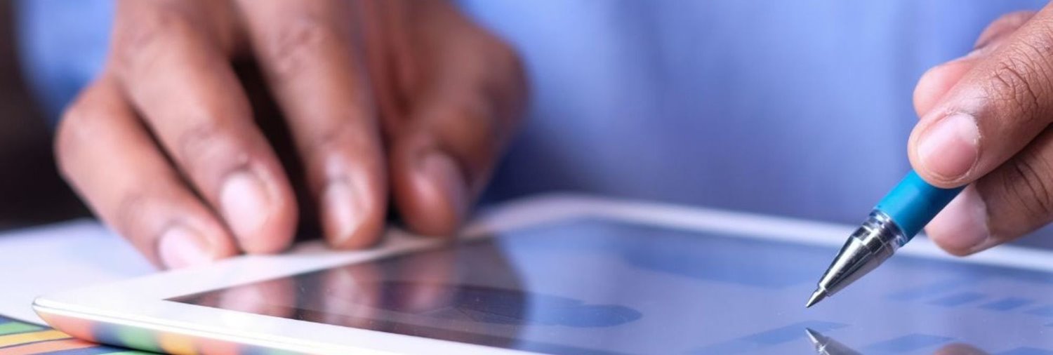 hand holding a pen pointing at a tablet