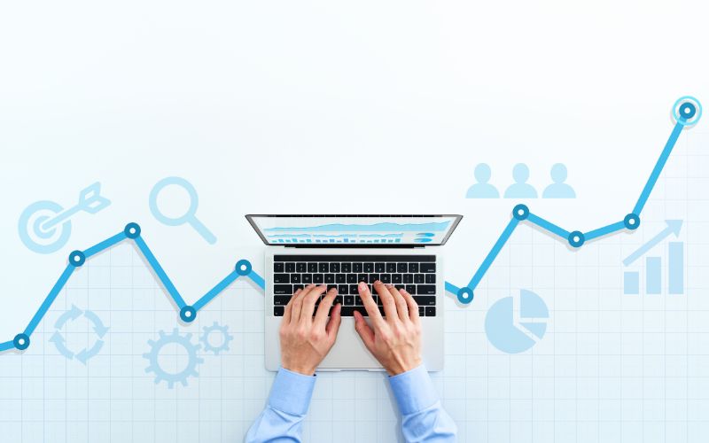 laptop with hands on it against a white background with graphics in the background showing growth