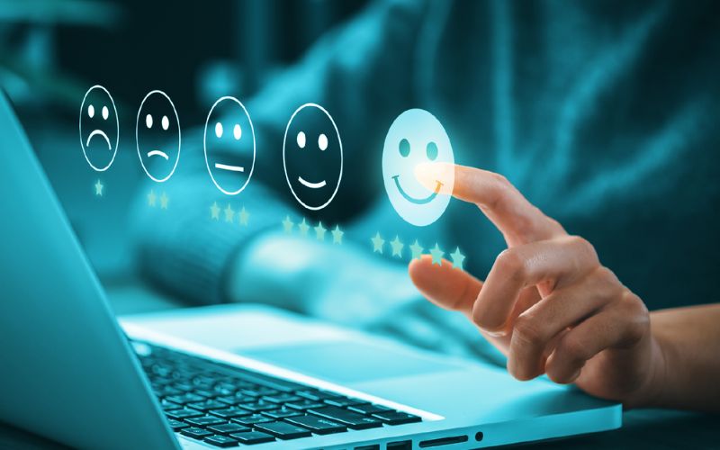 person sitting at laptop pointing at a graphics in the foreground of rating faces