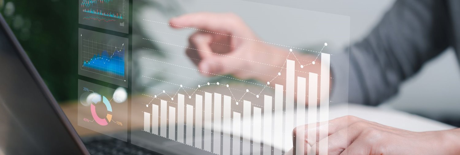 Graphs in the foreground while person types on laptop in background