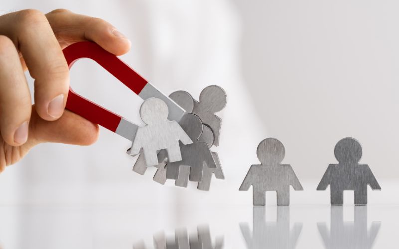 hand holding magnet attracting metal figures of people