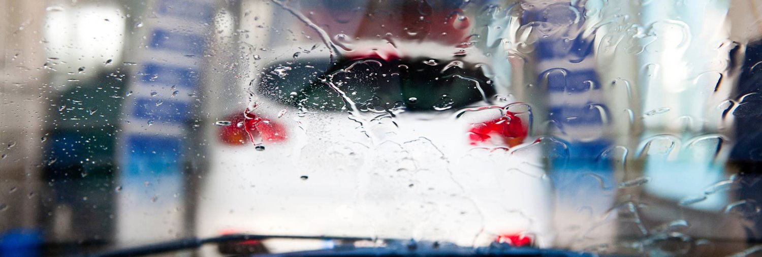 blurred image of white car in an in-bay automatic car wash