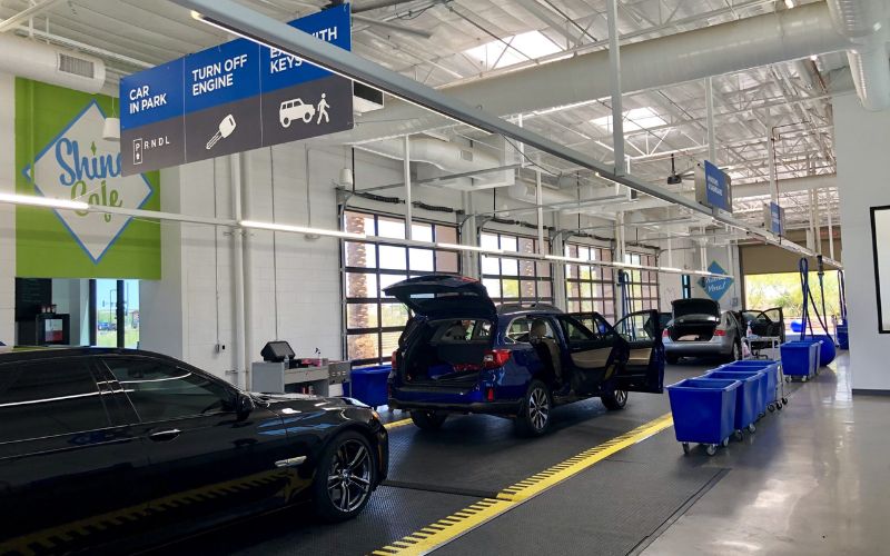 cars lined up in a detailing bay with doors and trunks open